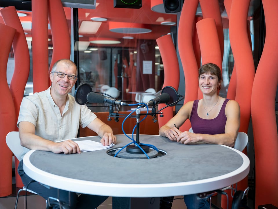 Markus Gasser und Nadia Zollinger sitzen vor zwei Mikrophonen.