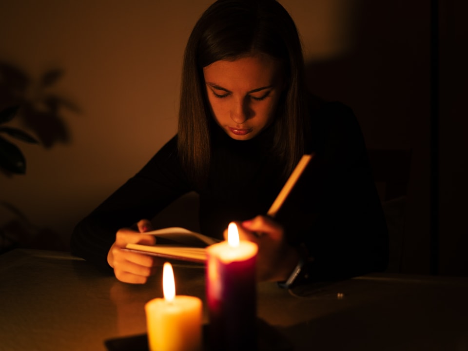Frau liest ein Buch im Kerzenlicht