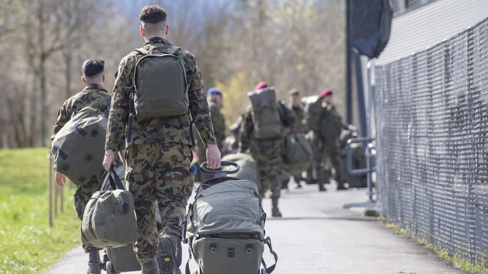 Mehrere Soldaten sind mit Gepäck beladen.