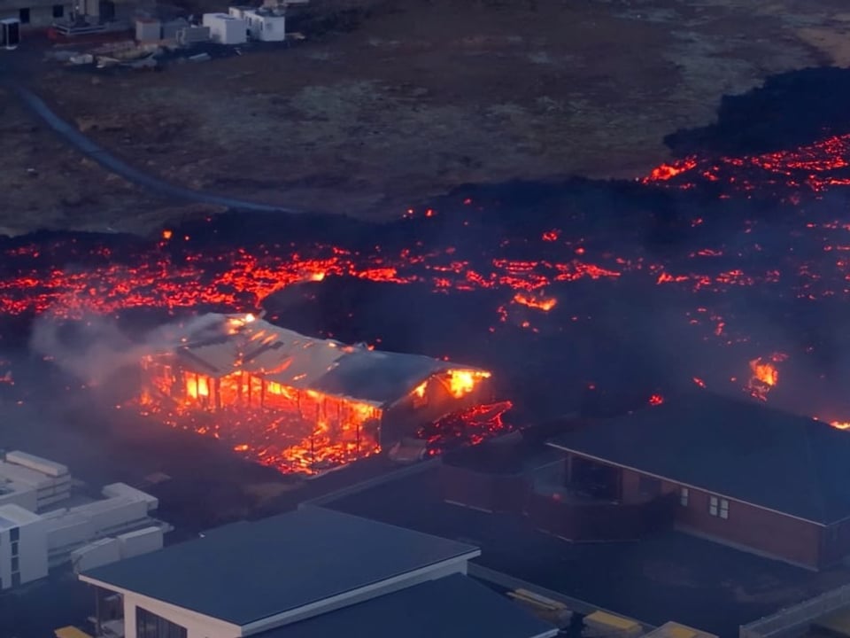 oranges Lawa hinter Häusern, ein Haus komplett zerstört, von Lava zerfressen