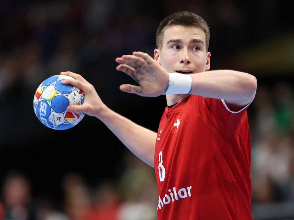 Handballspieler in rotem Trikot wirft den Ball.