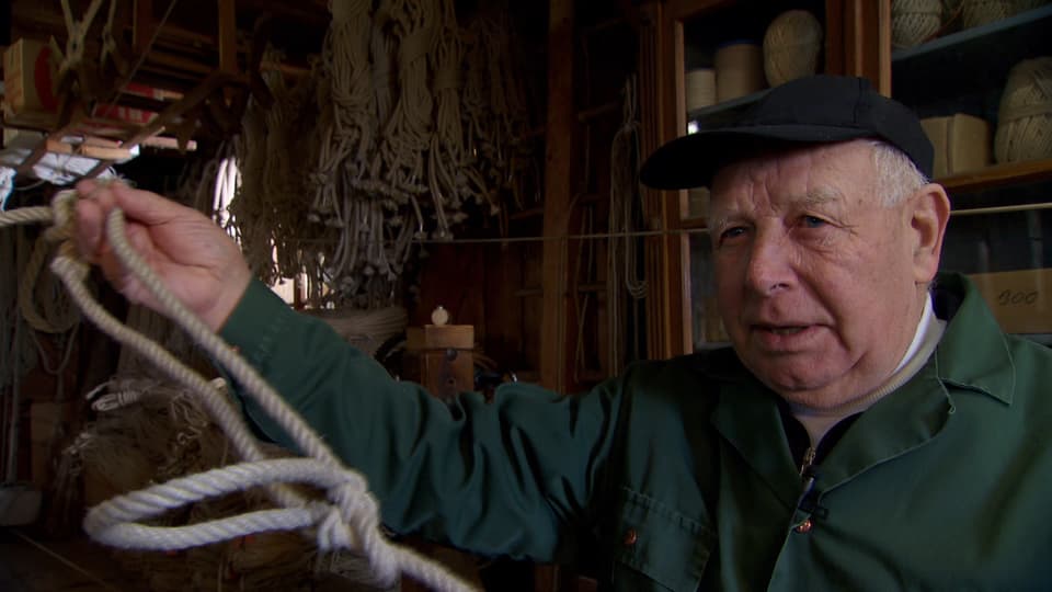 Ein alter Seilermeister mit einem Strick in der Hand. 