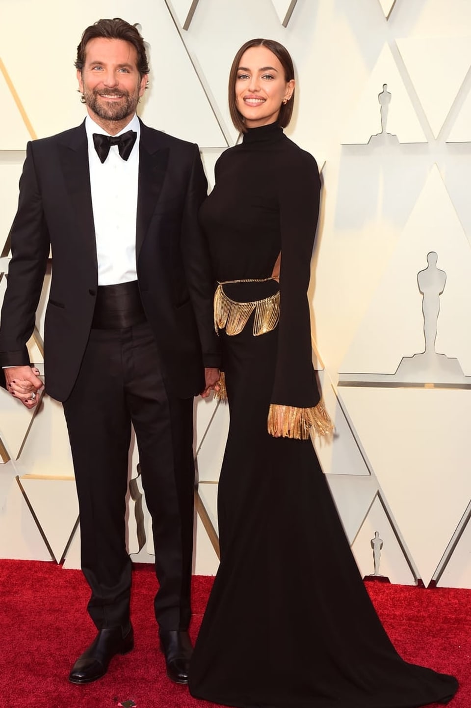 Bradley Cooper in einem schwarzen Anzug und Irina Shayk in einer schwarzen Robe