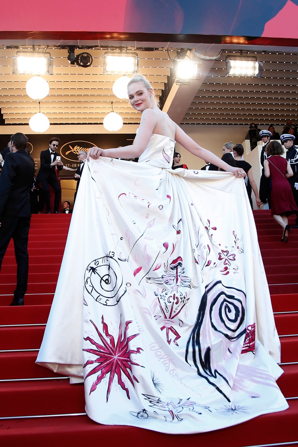 Schauspielerin Elle Fanning  in einen grossen weissen Kleid mit Zeichnungen