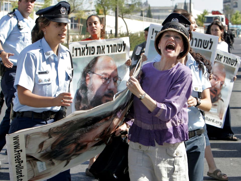 Eine wild schreiende Demonstratin hält ein Schild unter ihrem Arm. Eine israelische Polizistin schreitet ein.