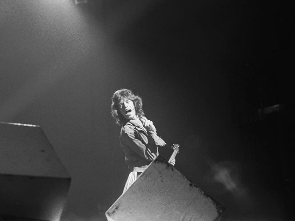 Mick Jagger steht auf der Bühne und spielt Gitarre
