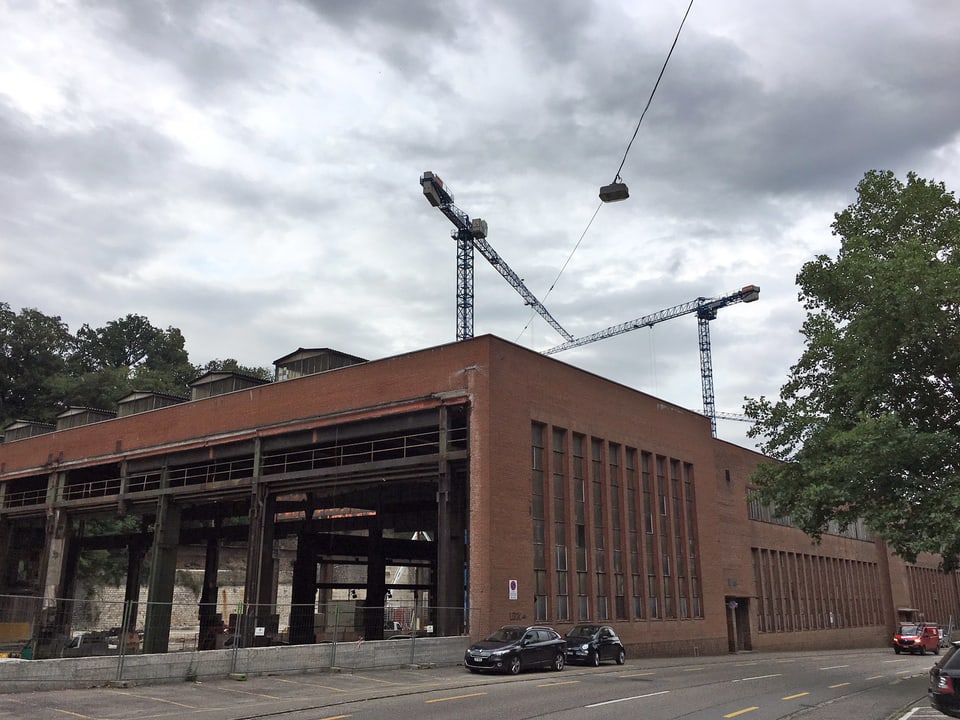 Backsteingebäude mit Baukränen an einer Strasse.