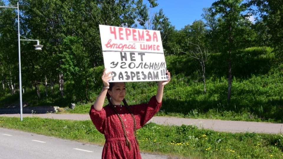 Eine Frau trägt ein russisches Schild bei einer Demonstration.