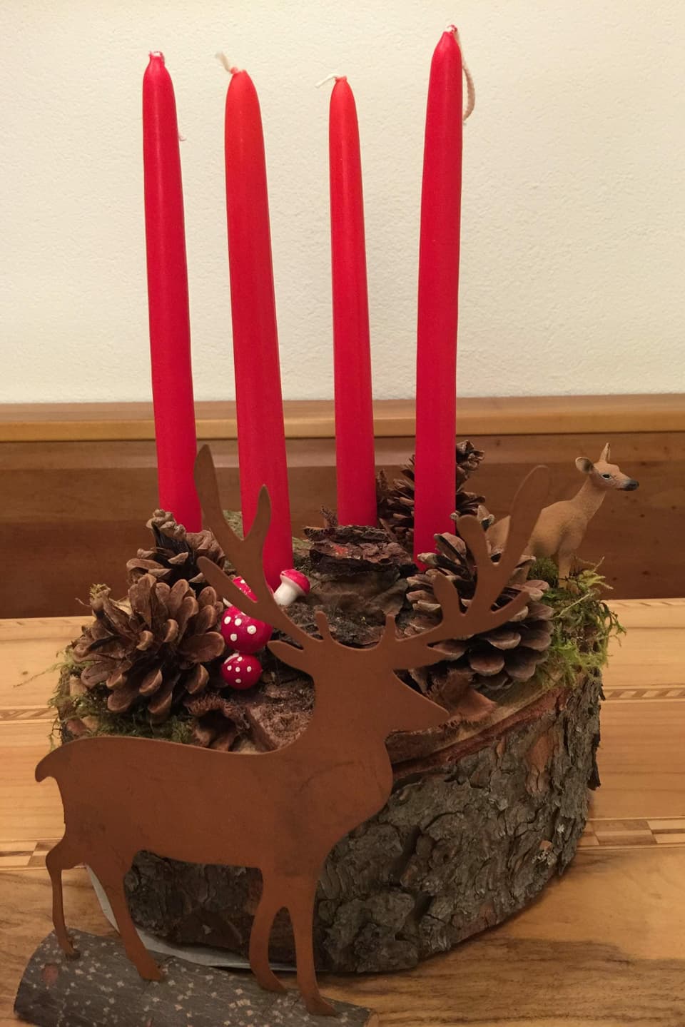 vier rote Kerzen auf einem Holzstamm.