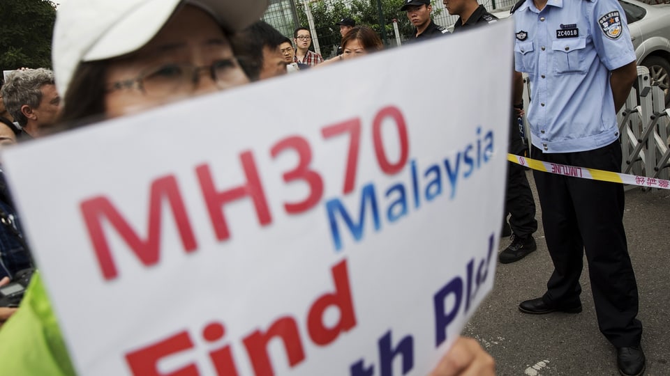 Angehörige hält an einer Kundegebung ein Schild in die Höhe mit der Aufschrift "MH370 Find the Plane"
