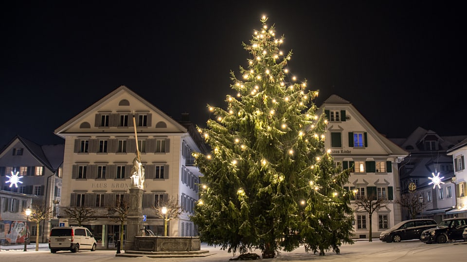 Grosser Weihnachtsbaum auf dem verschneiten Dorfplatz in Stans. 