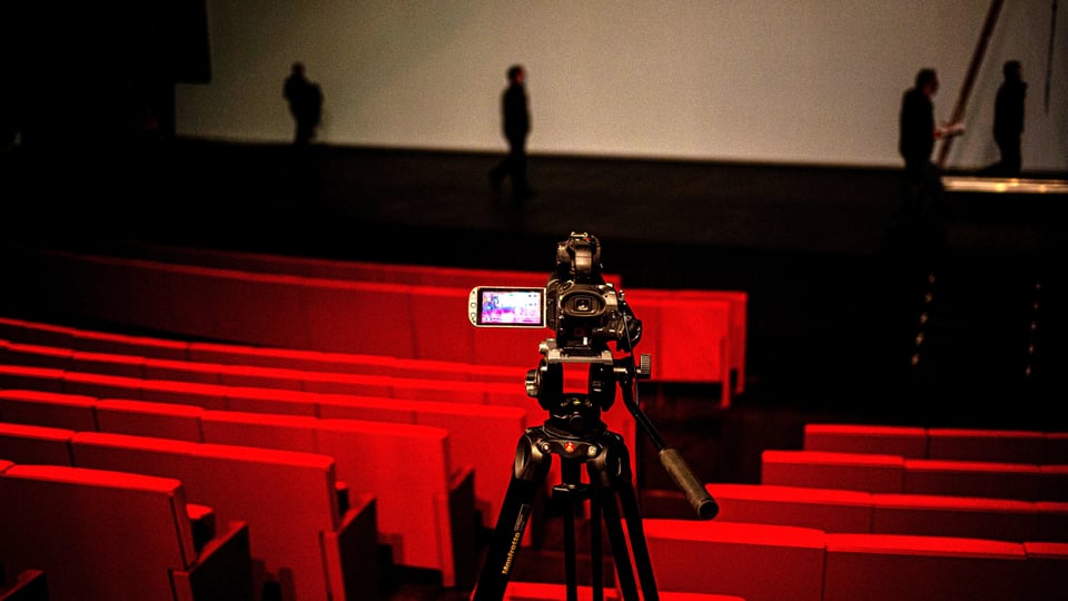 Eine Videokamera steht neben leeren Sitzen in einem Theater.