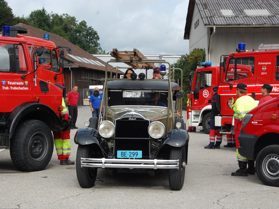 Altes Feuerwehrauto fährt durch Spalier von neuen Fahrzeugen.