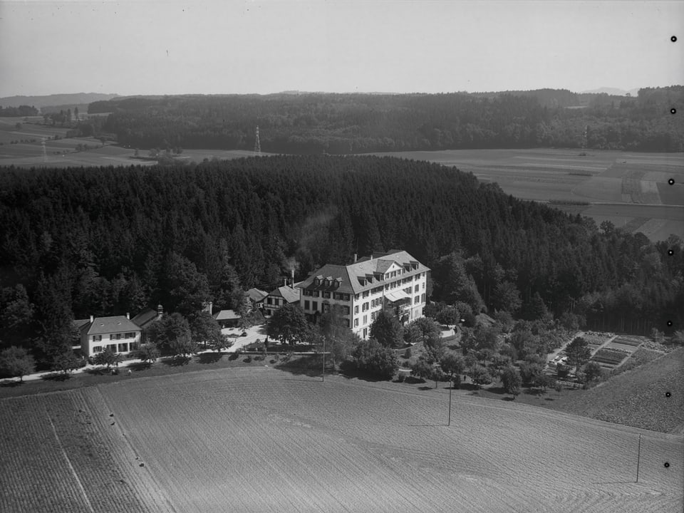 Ein grosses Haus an einem Waldrand.