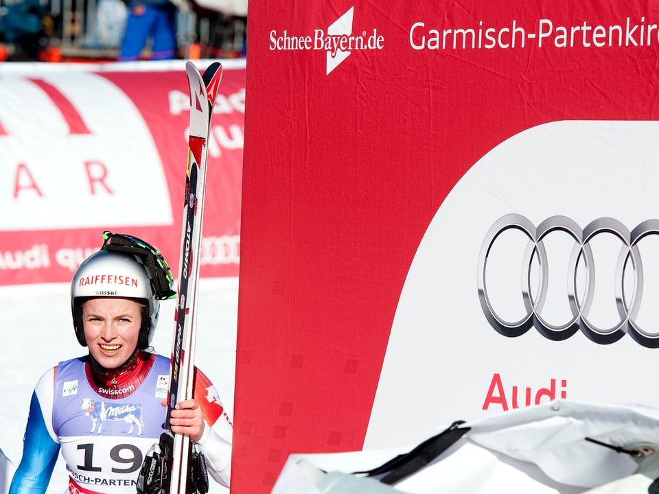 Lara Gut steht in Garmisch neben dem Podest und blickt blinzelnd in die Sonne.