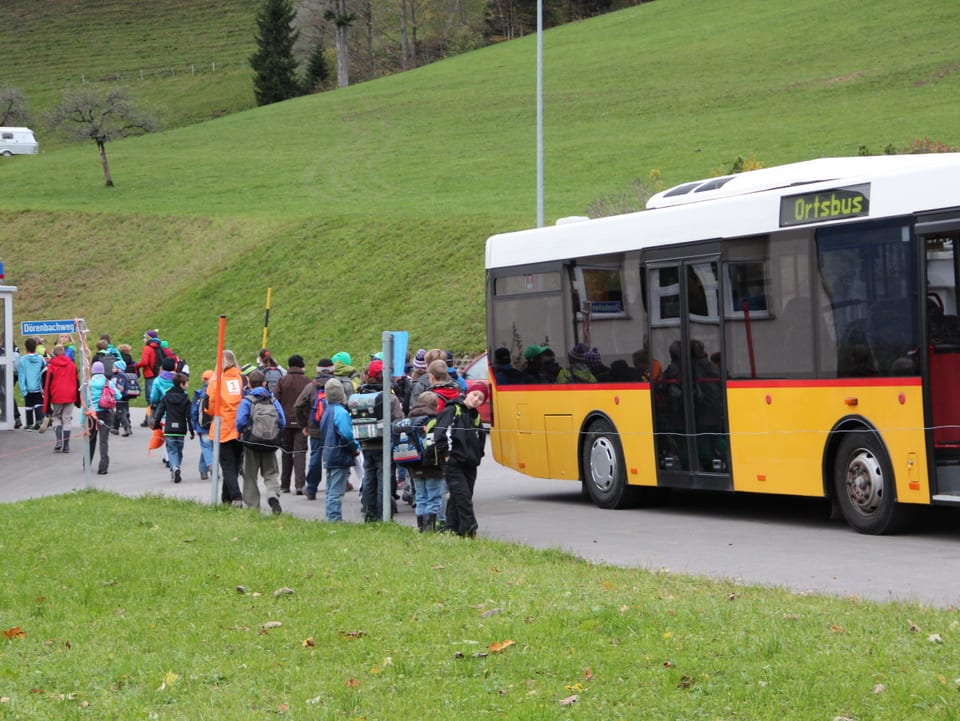 Kinder steigen aus Bus aus und laufen in die Schule.