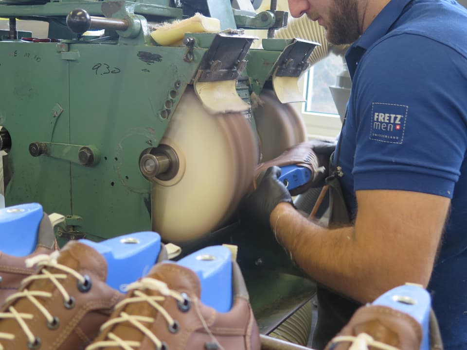 Arbeiter schleift Schuhsohle an Maschine