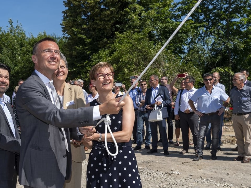 Der Konzernleiter der SBB, Jaques Boschung, und Regierungsrätin Sabine Pegoraro rollen beim Spatenstich des Gleisausbaus in Liestal ein Plakat aus. 