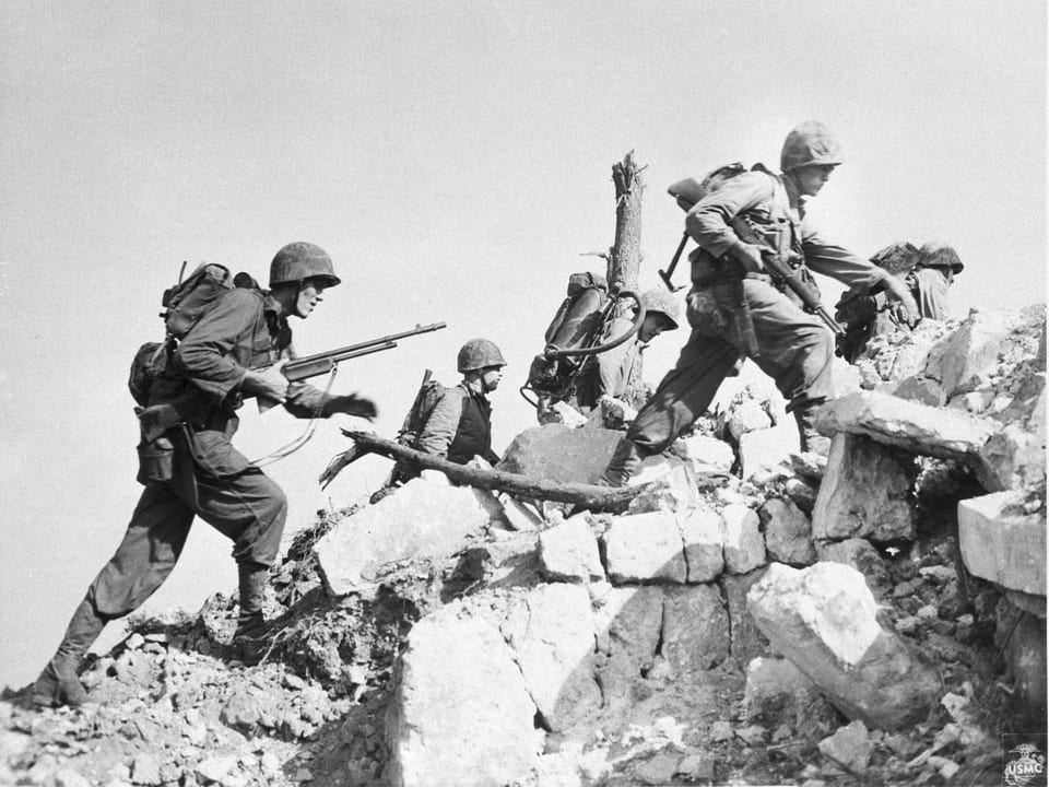 Soldaten überqueren einen Trümmerhügel.