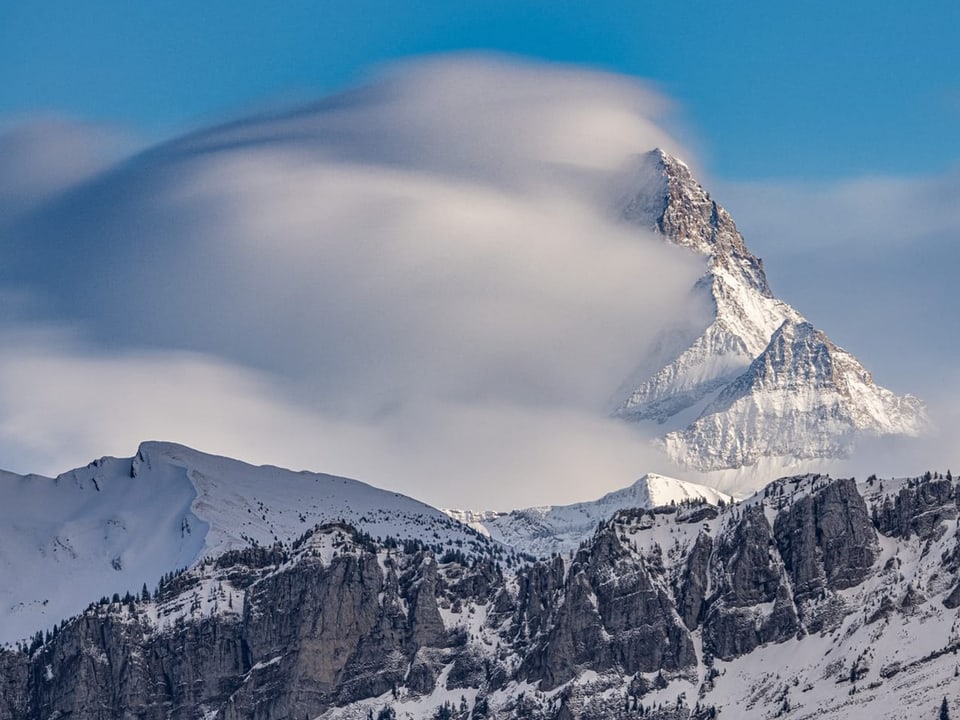 Berge mit Schnee, die linken Flanken sind in Wolken gehüllt. 