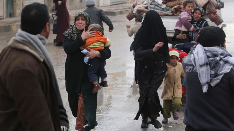 Frauen nördlich von Aleppo, Syrien, rennen mit Kindern im Arm und an der Hand auf die Kamera zu.