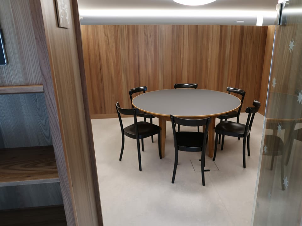 Ein runder Tisch mit Holzstühlen in einem Raum mit dunklen Holzwänden.
