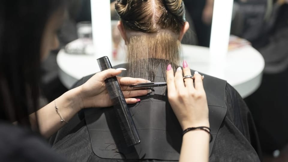 Eine Coiffeuse schneidet einer Kundin die Haare