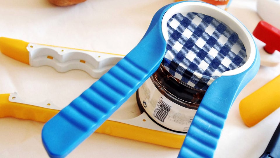 Speziell designter Drehverschlussöffner, der wie eine Zange um den Deckel eines Konfitürenglases sitzt.