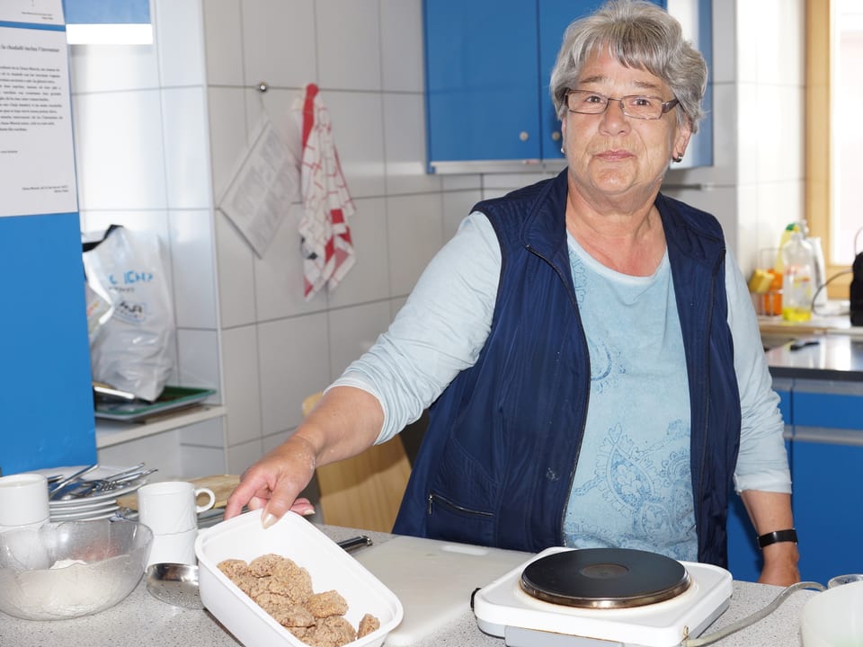 Eine Frau steht vor einer Kochplatte in einer Küche.