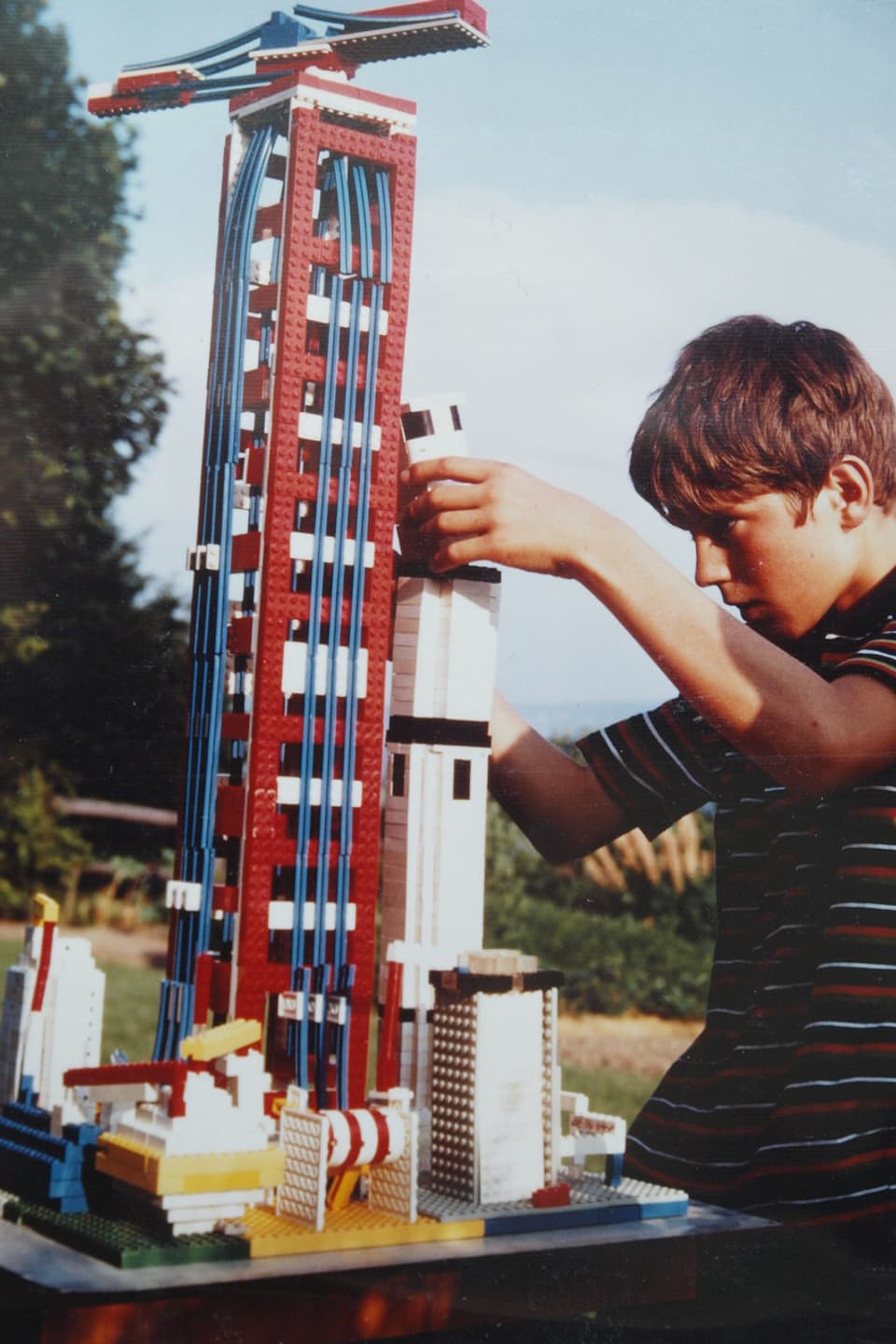 Das Bild zeigt ein altes Foto von einem Jungen mit einer grossen Raktete inklusive Startturm. 