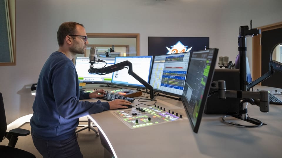 Ein Mann steht in einem Radiostudio und spricht in ein Mikrofon.