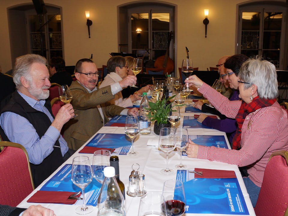 Ein paar Gäste an den Tischen prosten sich mit einem Glas Wein zu.