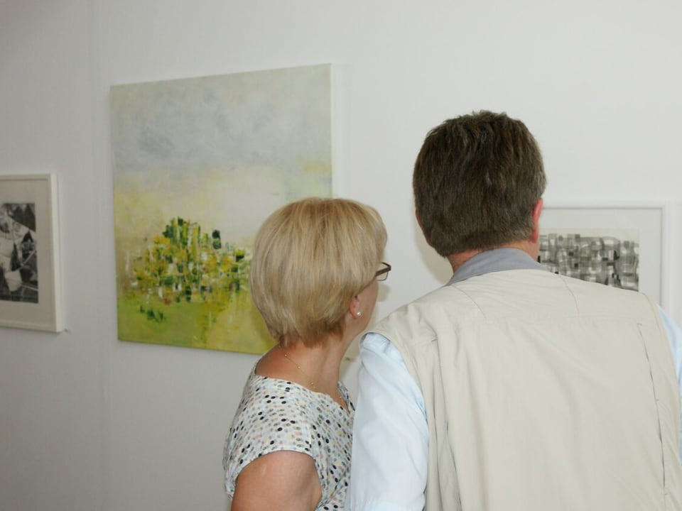 Zwei Besucher betrachten Gemälde und diskutieren.