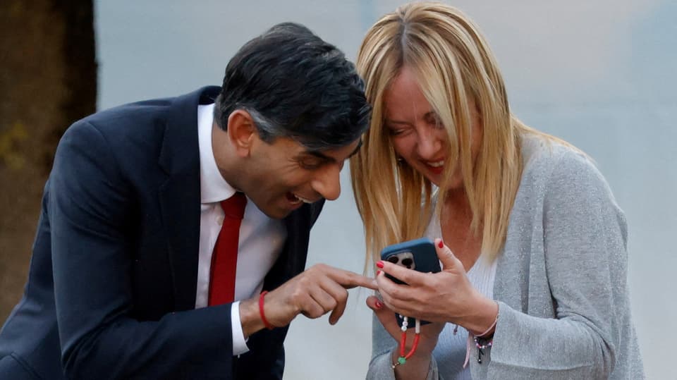 Mann und Frau lachen und schauen auf Smartphone.