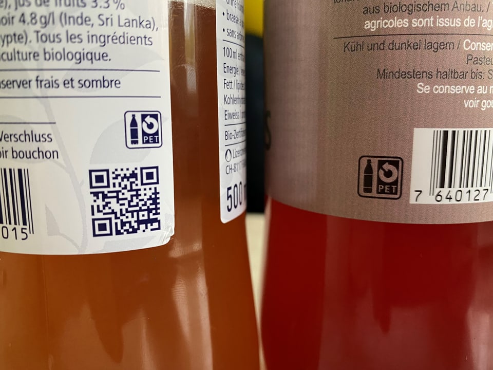 Nahaufnahme von zwei Flaschen-Etiketten mit dem PET-Zeichen: einem runden Pfeil und einer Flasche.