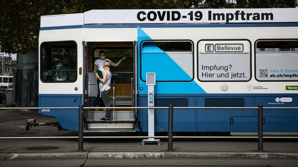 Zwei Personen stehen bei der Tür eines Impftrams in Zürich.