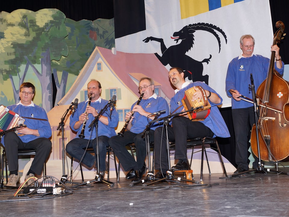 Die Musikanten der Ländlerkapelle spielen sitzend und stehend ihre Instrumente.