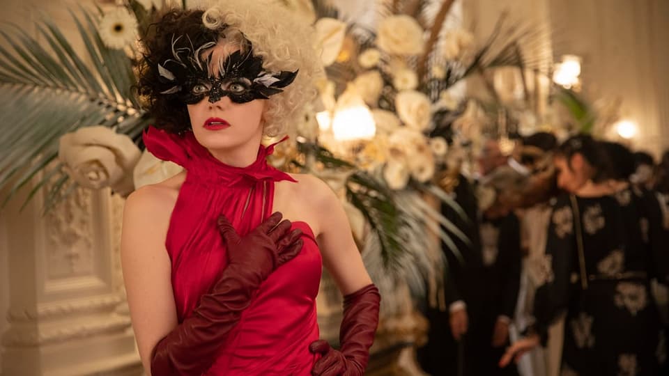 Filmszene: Frau in rotem Abendkleid mit schriller Federbrille