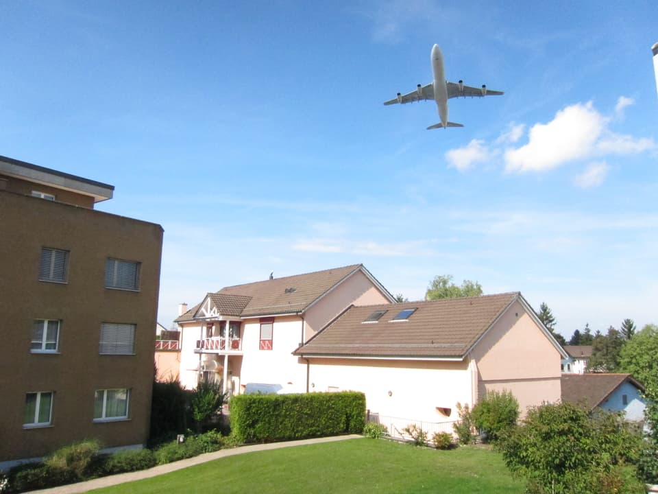 Ein Flugzeug fliegt über ein Wohngebiet.