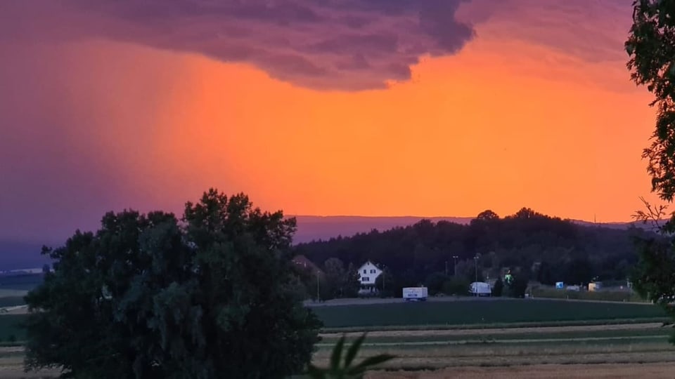 Leuchtendes Abendrot über dem Zürcher Weinland mit grauen Gewitterwolken im Vordergrund