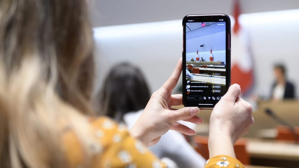 Eine Frau macht einen Livestream einer Bundesrat-Pressekonferenz