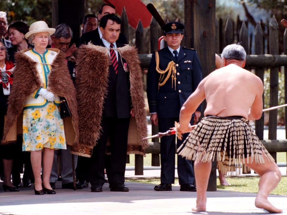 Die Queen trägt einen traditionellen Maori-Mantel und schaut 