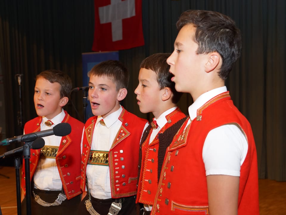 Die vier Burschen tragen eine rot-weisse Appenzeller Tracht und singen zu viert ins Mikrofon.