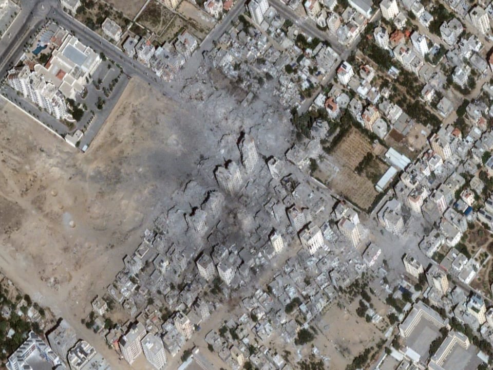 Satellitenaufnahme von einem Quartier einer Stadt. In der Bildmitte sind Trümmer und teilweise zerstörte Gebäude.