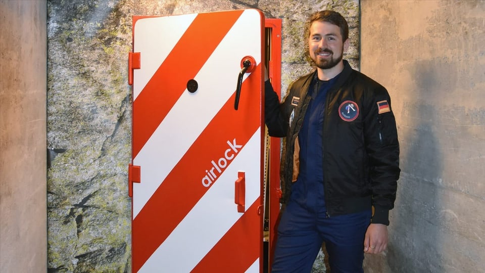 Mann vor Bunkertür mit der Aufschrift «Airlock».