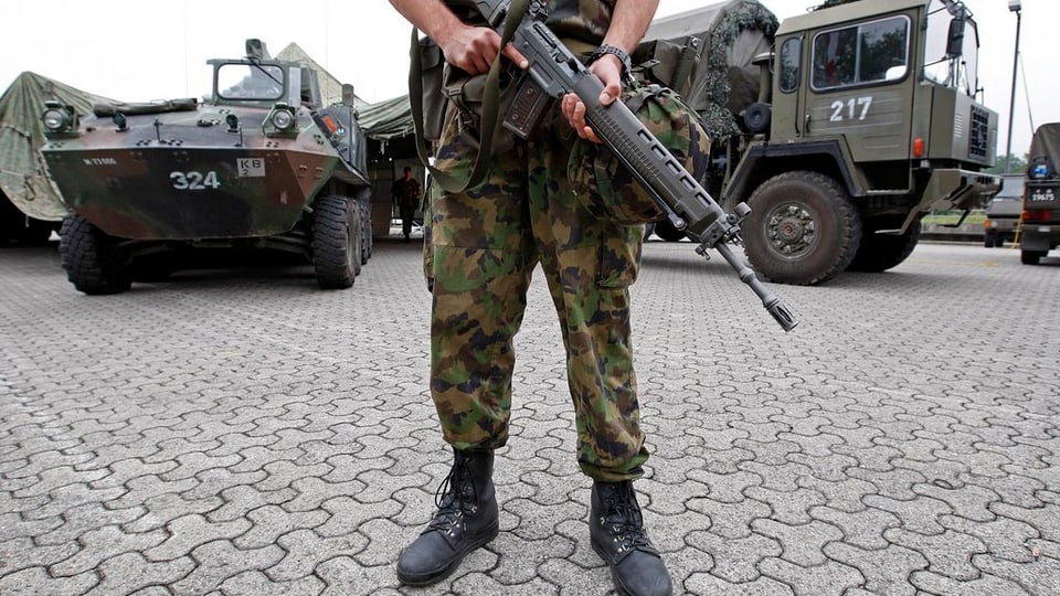 Ein Soldat bewacht mit Gewehr Fahrzeuge auf einem Platz in Bremgarten.