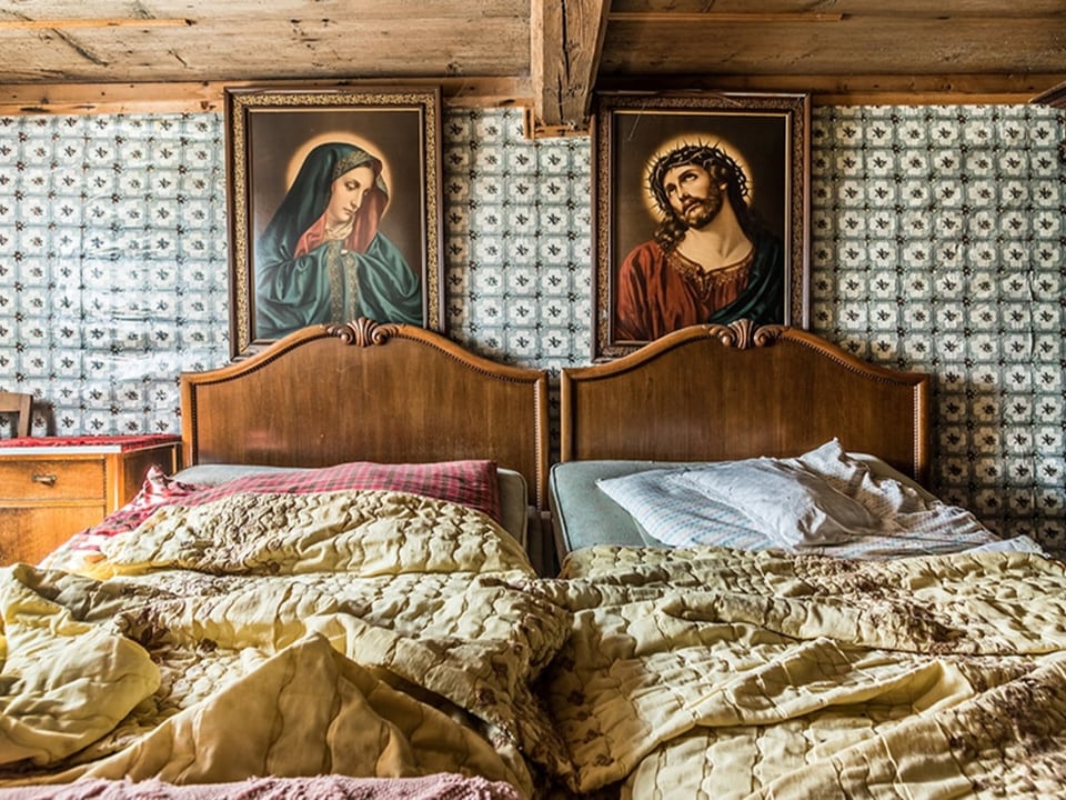 Bett mit Bettwäsche und Bildern von Maria und Jesus.