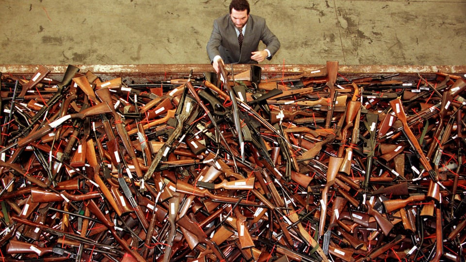 Ein Polizist aus Sydney blickt auf einen Berg Waffen, die 1997 im Zuge des neuen Gesetzes zurückgegeben wurden.