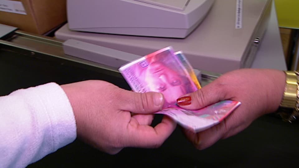 Eine Person übergibt einer Frau an der Kasse 30 Franken.