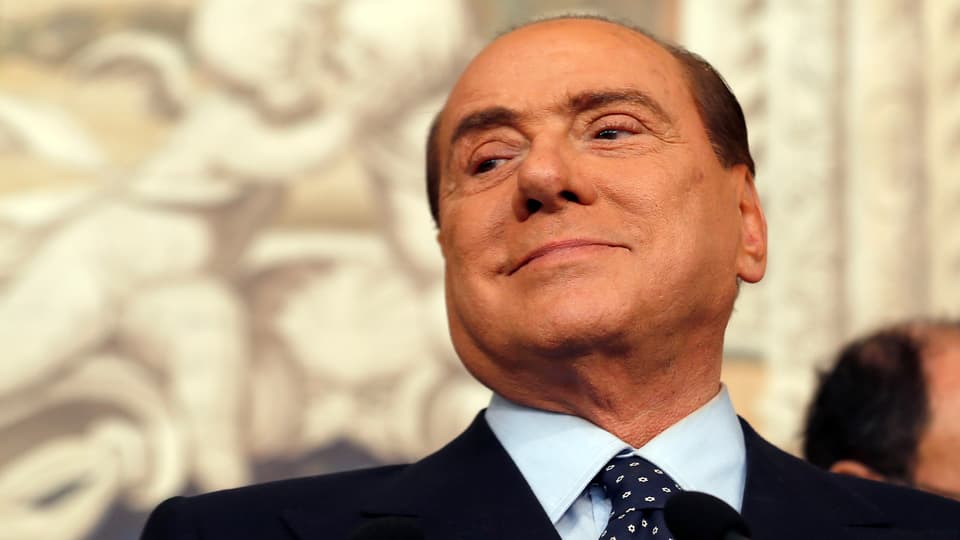 Berlusconi hebt den Kopf und schaut erleichtert auf die untere Seite.